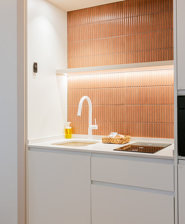 Cocina equipada con azulejos terracota Cocina con placa de inducción, fregadero y pared de azulejos color terracota en un apartamento turístico de Grupo CCOMMO