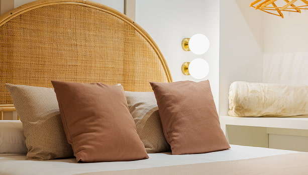 Dormitorio de Los 6 Dormitorio de Los 6 con cabecero de ratán, cojines en tonos terracota y beige y apliques de globo